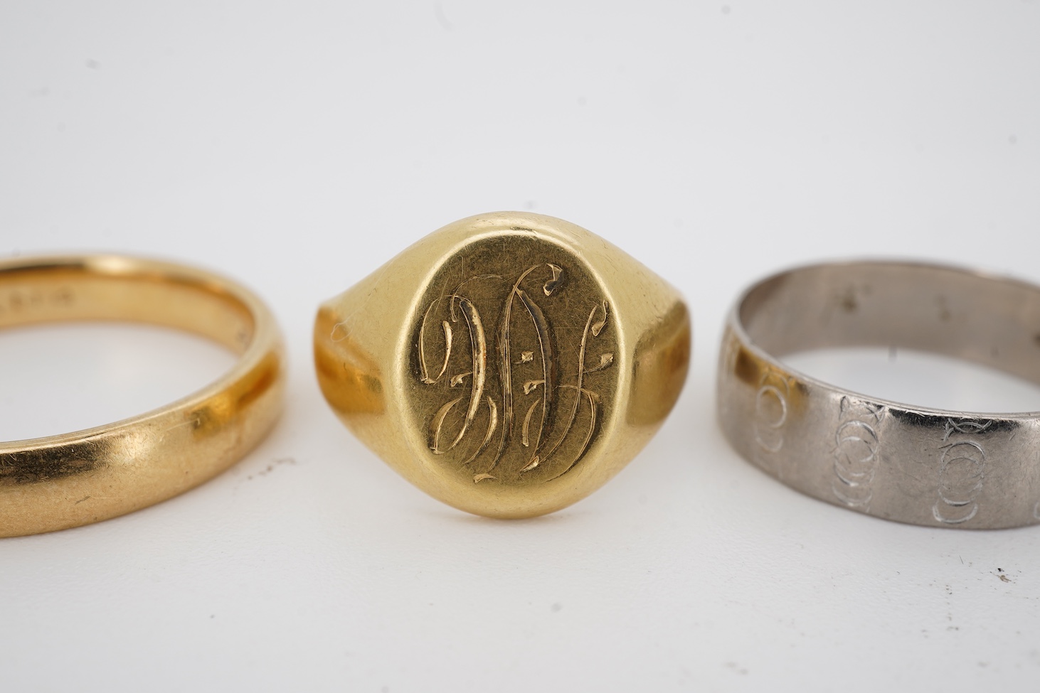 A 1990's 18ct gold wedding band, with engraved inscription, size U/V, a similar signet ring with engraved monogram and inscription, size I and an early 1970's 18ct white gold band, size O, gross weight 15.4 grams.